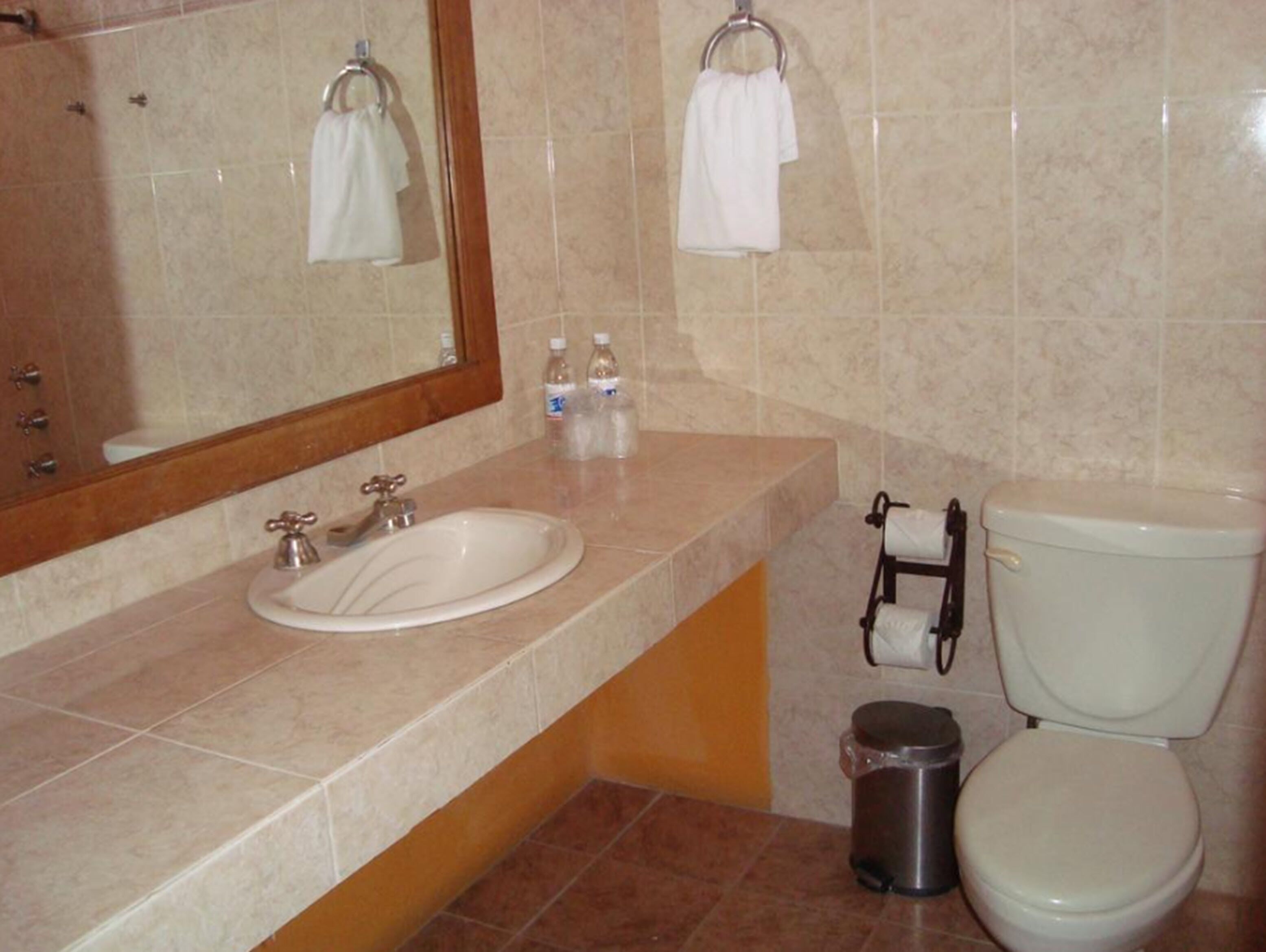 A bathroom with a sink, toilet, and a trash can.