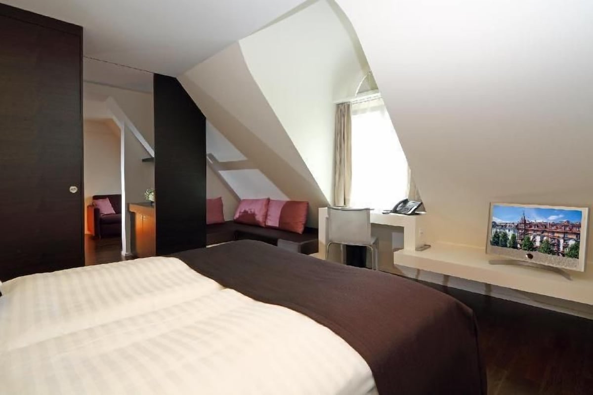 Ein Schlafzimmer mit einem großen Bett, einem Schreibtisch, einem Stuhl und einem Bild an der Wand.
