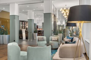 Relax in our inviting lobby, featuring a comfortable seating area with armchairs and ottoman, elegant lighting, and lush greenery.