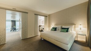 A spacious hotel room with a large bed, a bedside table with a lamp, and a view of the city through the window. - Residence Hotel (Vaduz)
