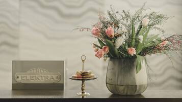 A metal container with a key, a metal plate with "ELEKTRA" engraved, and a metal stand with macarons.