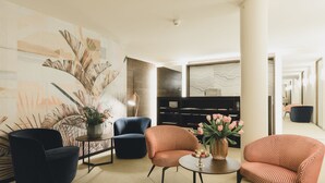 A modern lounge area with a large abstract mural, two armchairs, a small round table, and a bookshelf. - Residence Hotel (Vaduz)