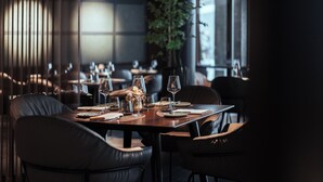 A restaurant interior with tables set for dining, chairs, and a large plant. - Residence Hotel (Vaduz)