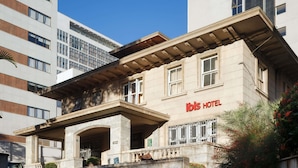 A hotel with a classic facade, a prominent entrance with a canopy, and the name 'ibis HOTEL' displayed. - Ibis Belo Horizonte Liberdade (Belo Horizonte)