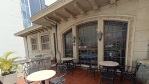 An outdoor patio with tables and chairs, a stone fountain, and a large arched window with stained glass. - Ibis Belo Horizonte Liberdade (Belo Horizonte)