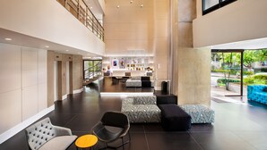 Un vestíbulo amplio con techo alto, asientos modernos y una zona de recepción con mostrador y computadoras.