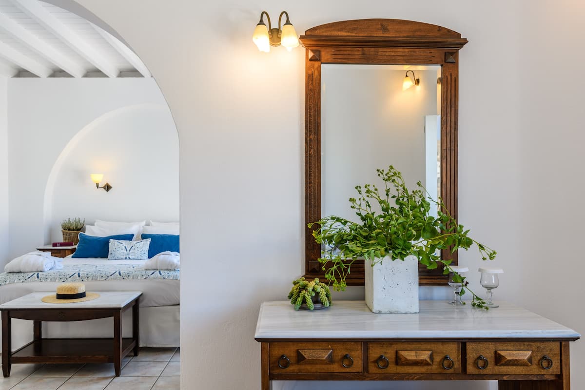 Un dormitorio con cama, mesita de noche y un espejo grande.