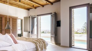Quarto com cama, teto de madeira, televisão e vista para uma piscina.