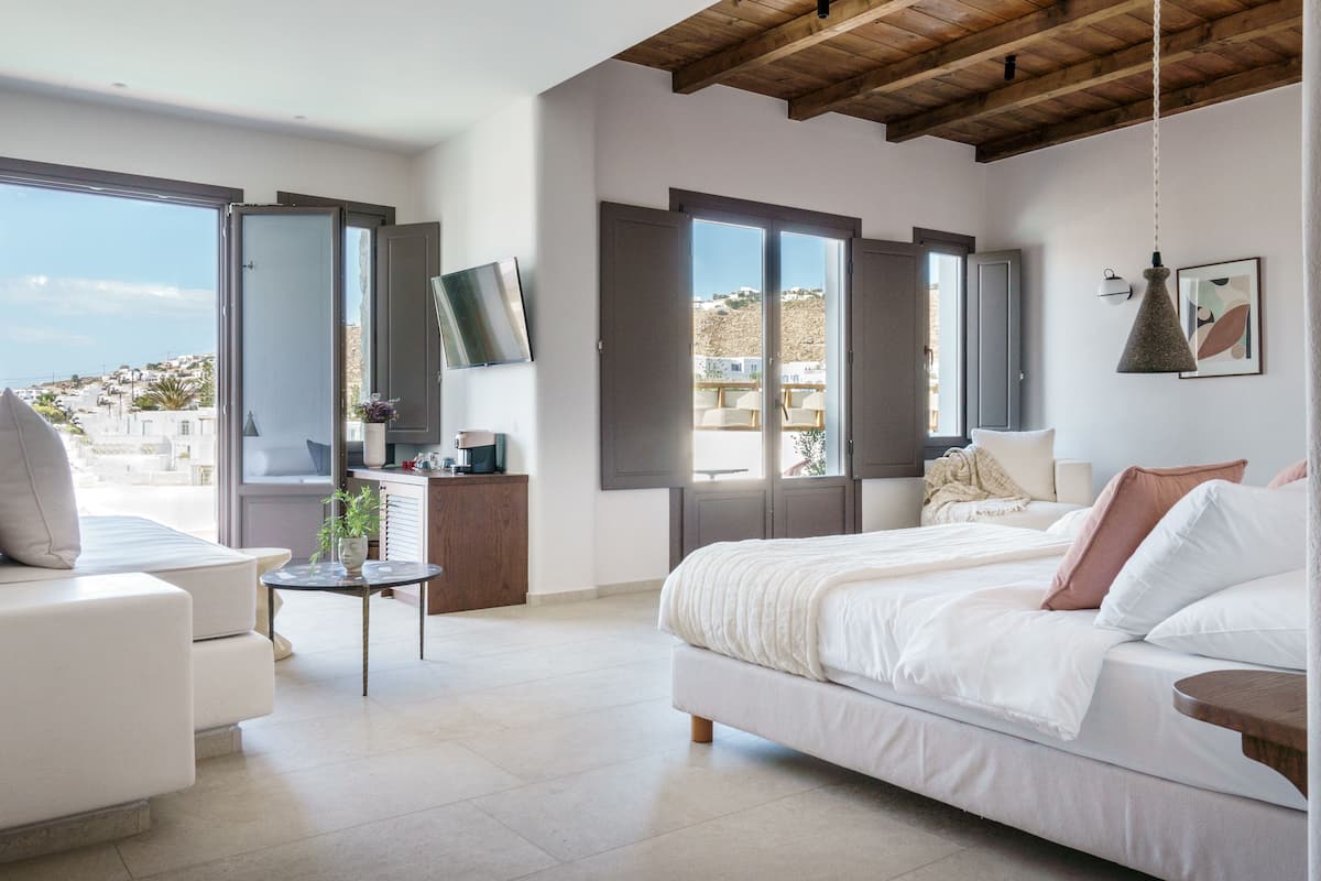 Un dormitorio moderno con cama, sofá, escritorio y televisor.