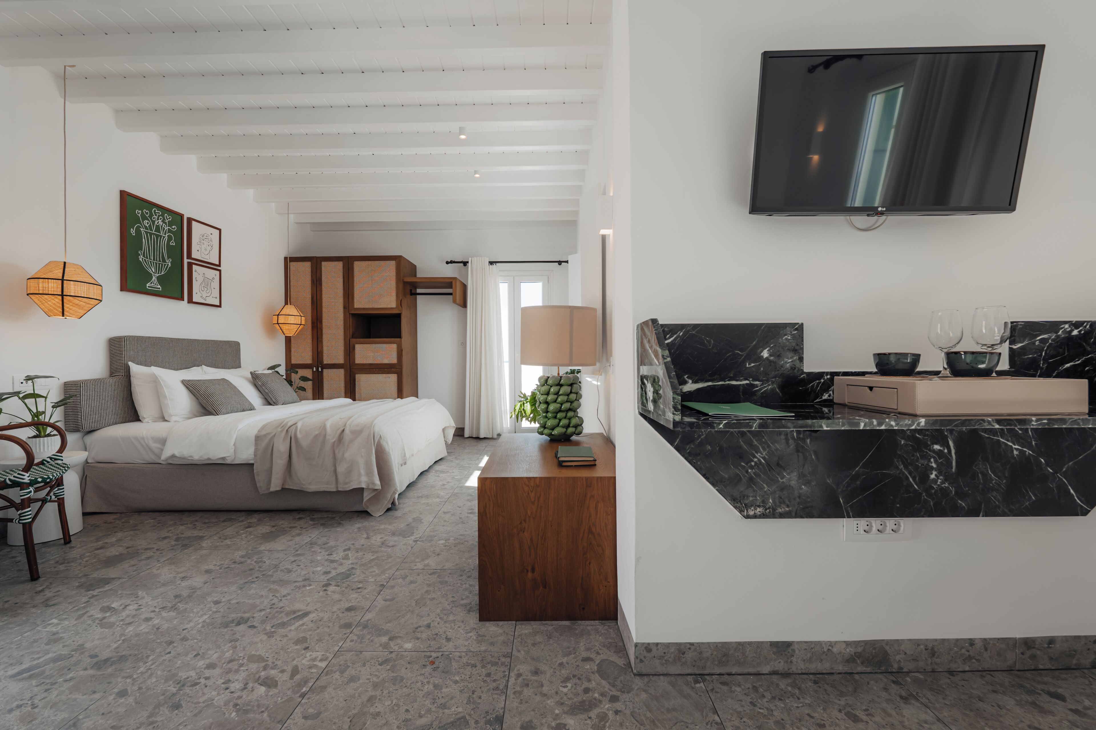 A modern bedroom with a bed, bedside table, and a TV mounted on the wall.