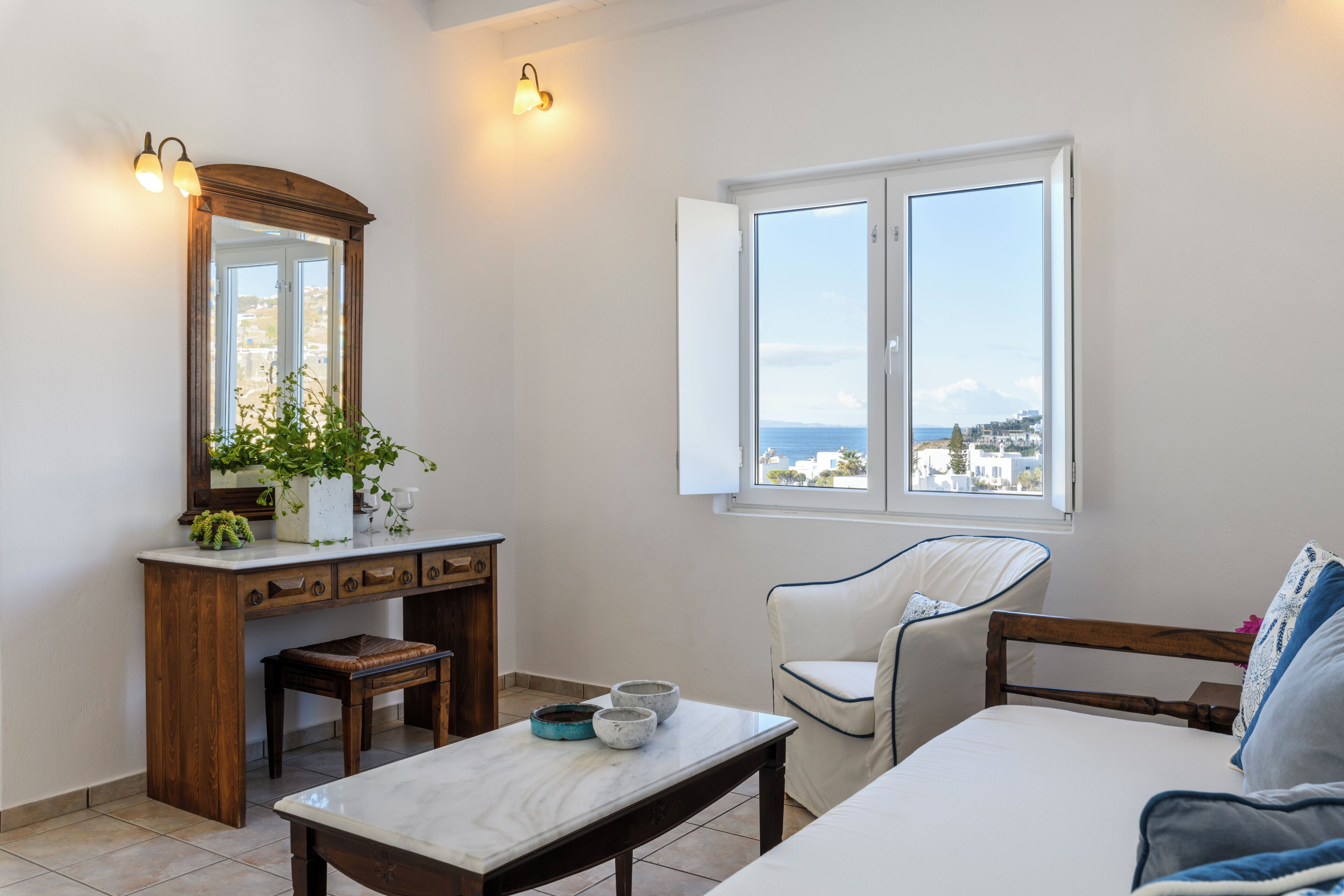 Une chambre à coucher avec un lit, une chaise, une table, un miroir et une fenêtre donnant sur un beau paysage.