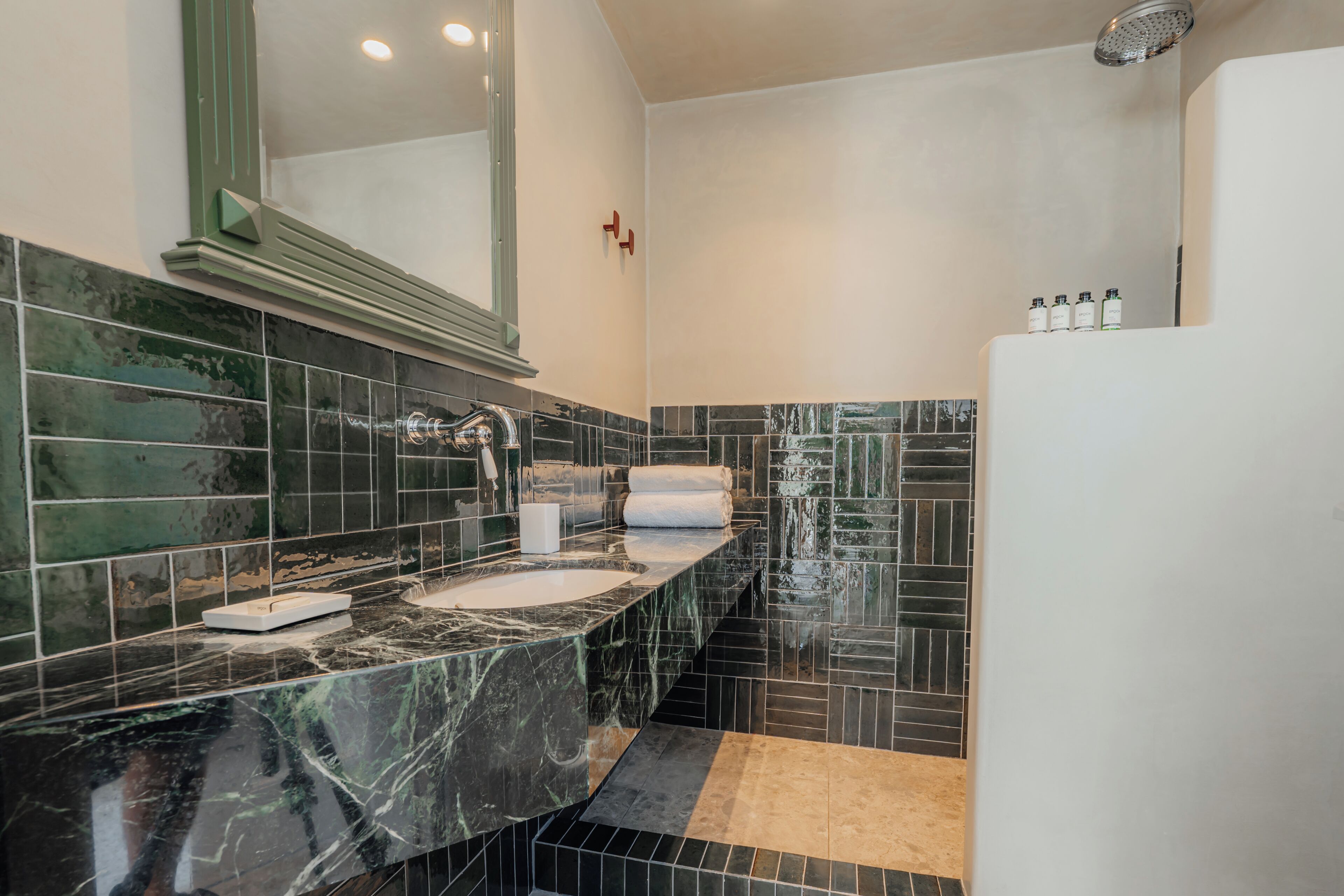 A modern bathroom with a marble sink, a large mirror, and a shower area.