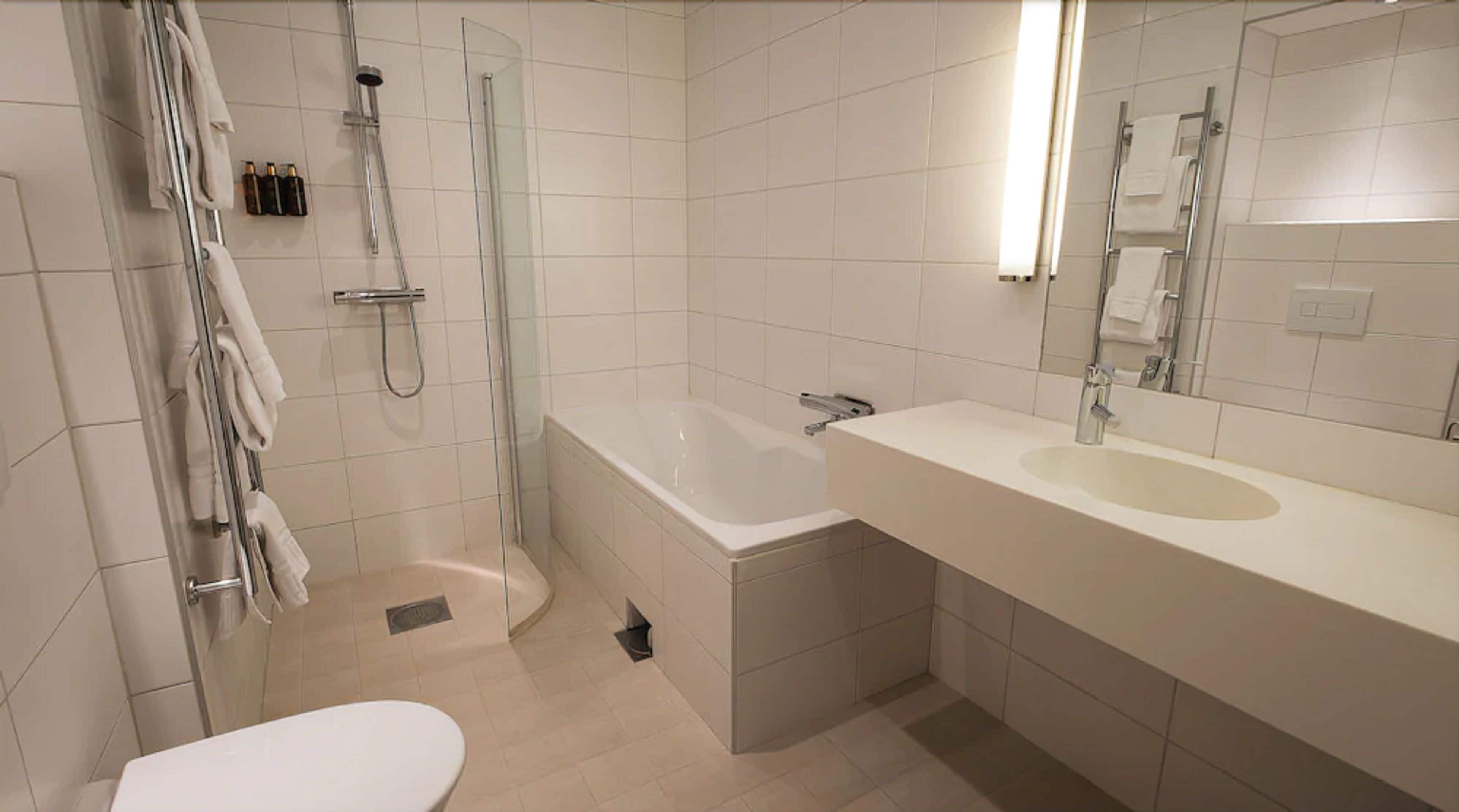 A modern bathroom with a glass-enclosed shower, a standalone bathtub, a toilet, and a vanity with a sink.