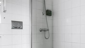 Un baño con inodoro, ducha y suelo de baldosas.