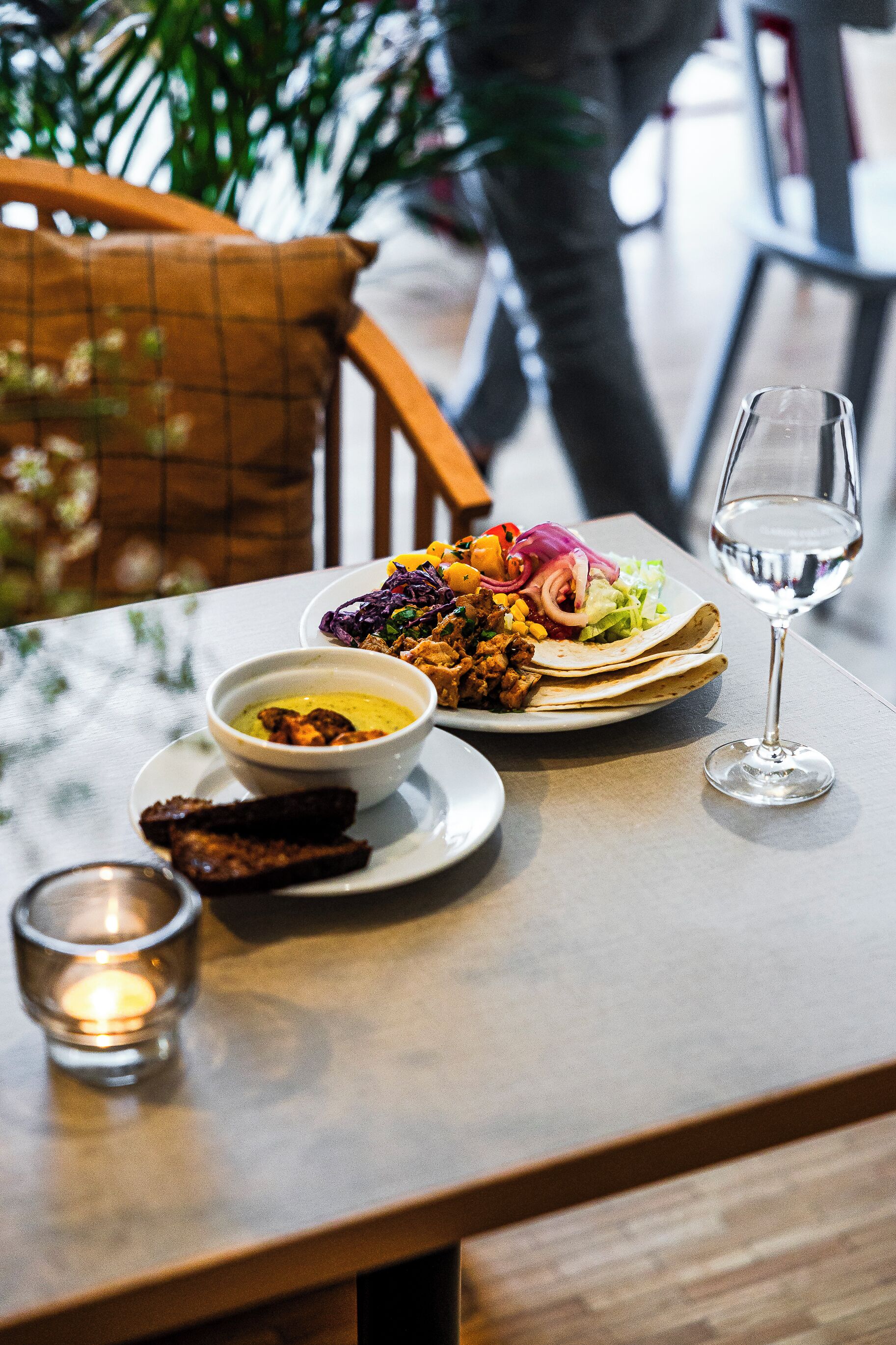 Et spisebord med en tallerken mad, en skål sauce og et glas hvidvin.