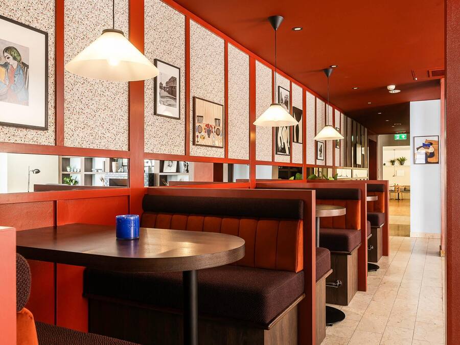 A restaurant with booths and tables, framed artwork on the walls, and pendant lighting.