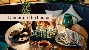 A cozy dining setup with a chessboard, a cup of tea, and a plate of food on a round table. - Home Hotel Grand Sundsvall (Sundsvall)