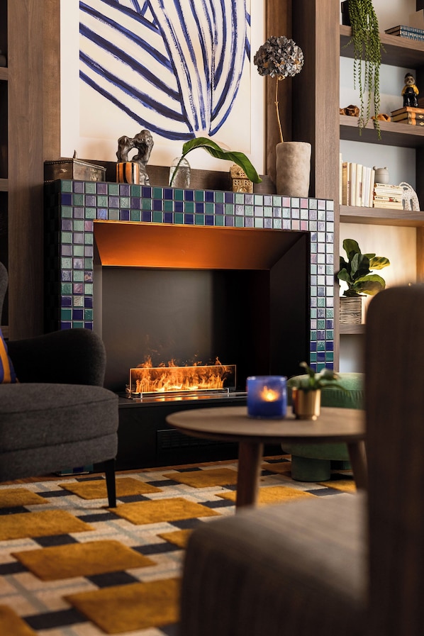 A modern living room with a fireplace, a sofa, a coffee table, and a patterned rug.