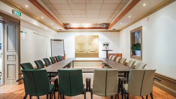 A conference room with a long table, chairs, a whiteboard, and a door labeled "GRAND".