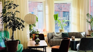 A modern living room with a sofa, chairs, a table, and potted plants. - Home Hotel Grand Sundsvall (Sundsvall)