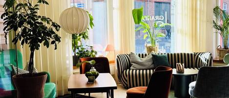 Una sala moderna con un sofá, sillas, una mesa y plantas en macetas.