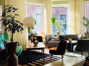 A modern living room with a sofa, chairs, a table, and potted plants.