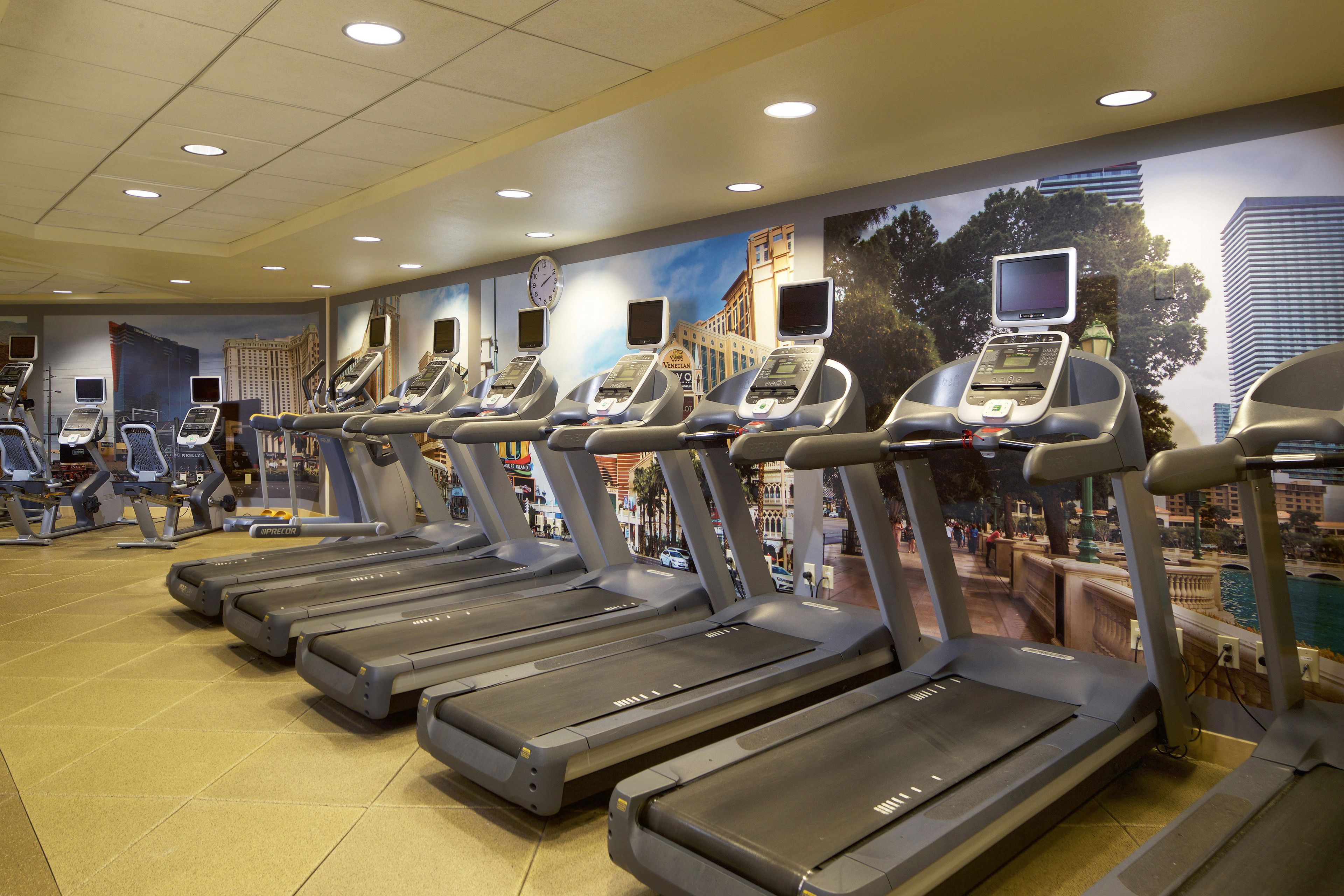Une salle de sport équipée de plusieurs tapis de course, chacun doté d’un écran numérique.