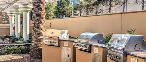 A patio area with outdoor grills and a palm tree.