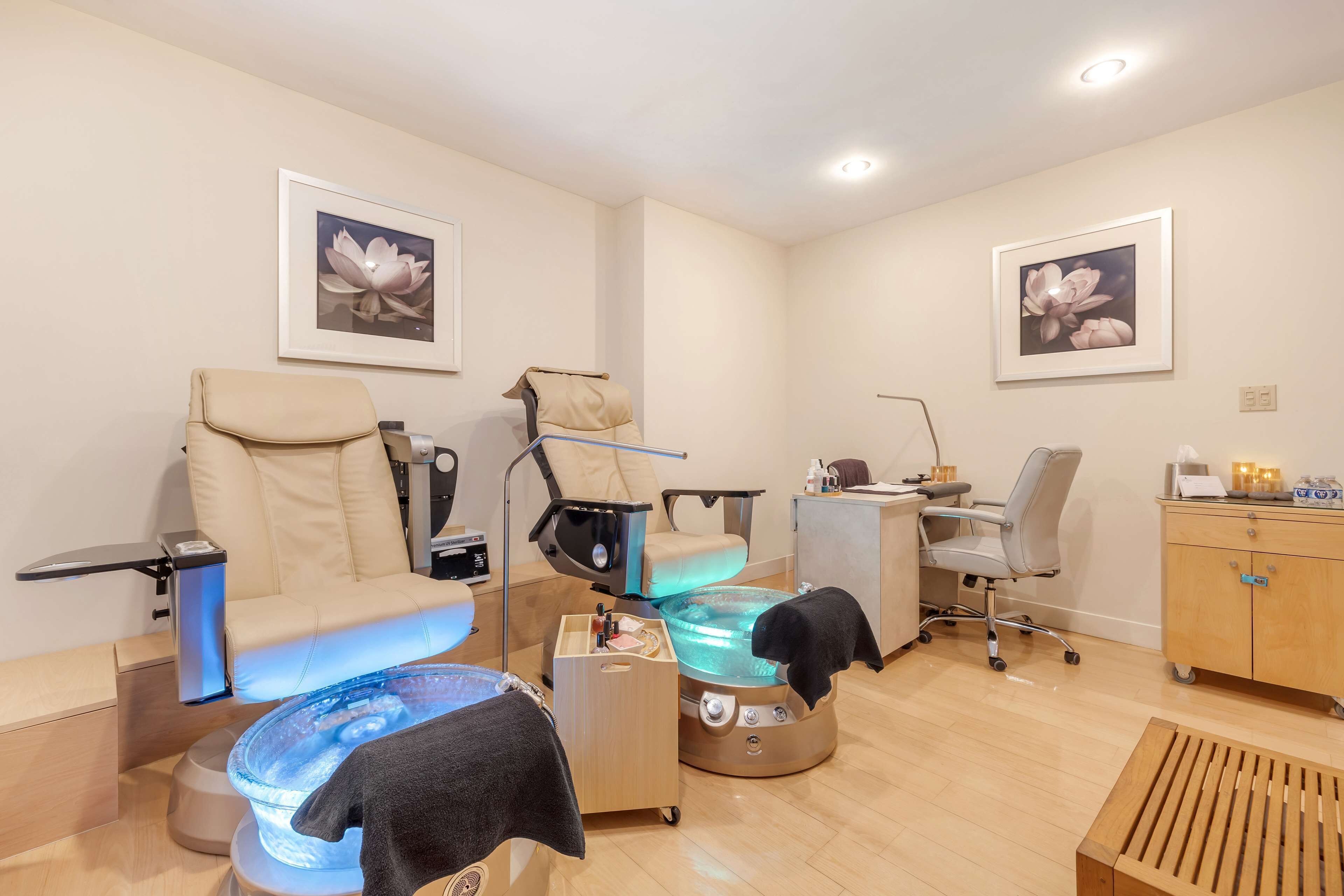 Un moderno spa con una silla de masaje, un recipiente para pies y un escritorio con ordenador.