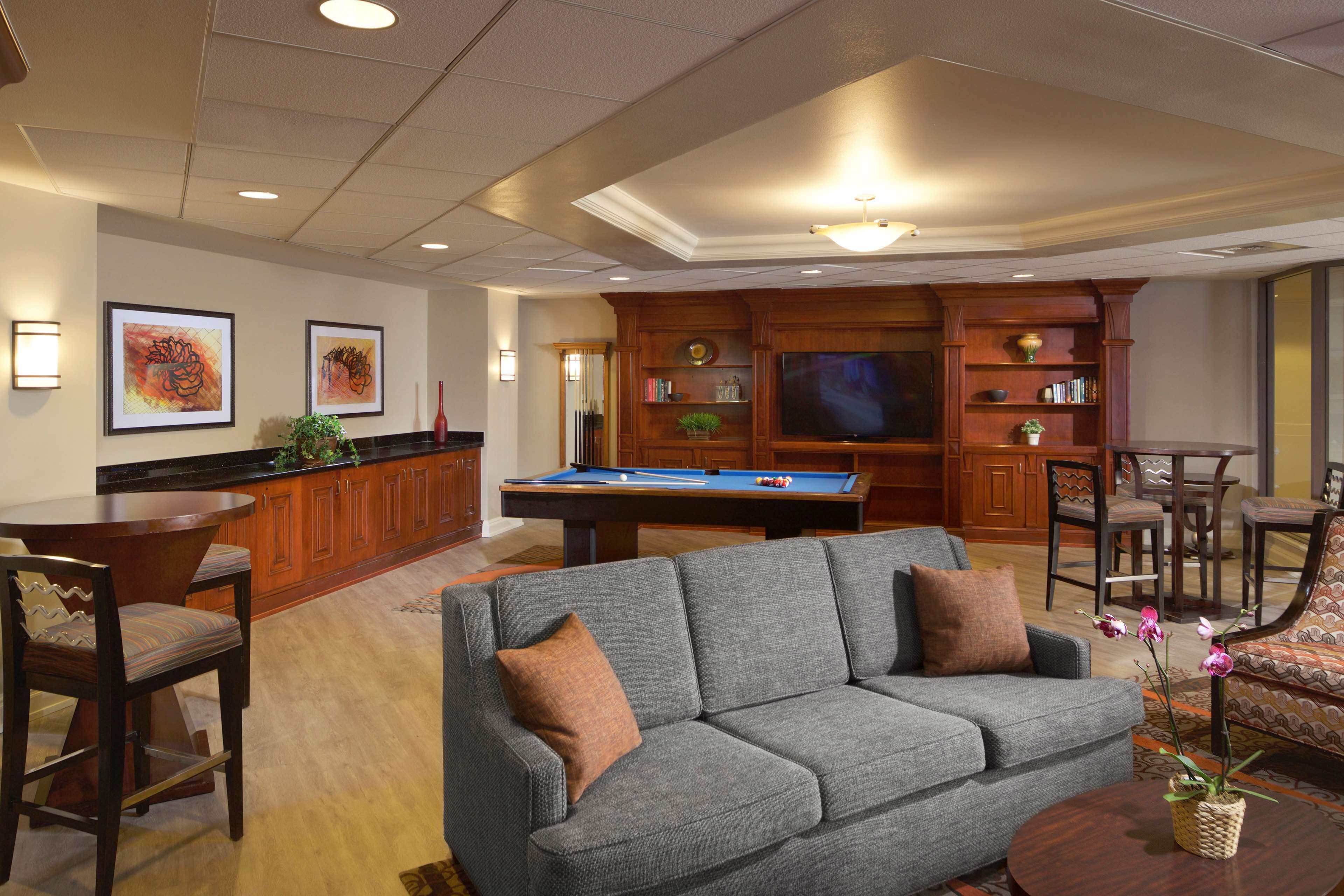 A living room with a pool table, a sofa, and a television.