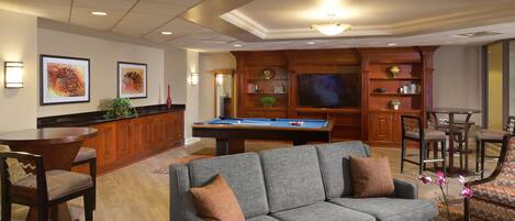 A living room with a pool table, a sofa, and a television.