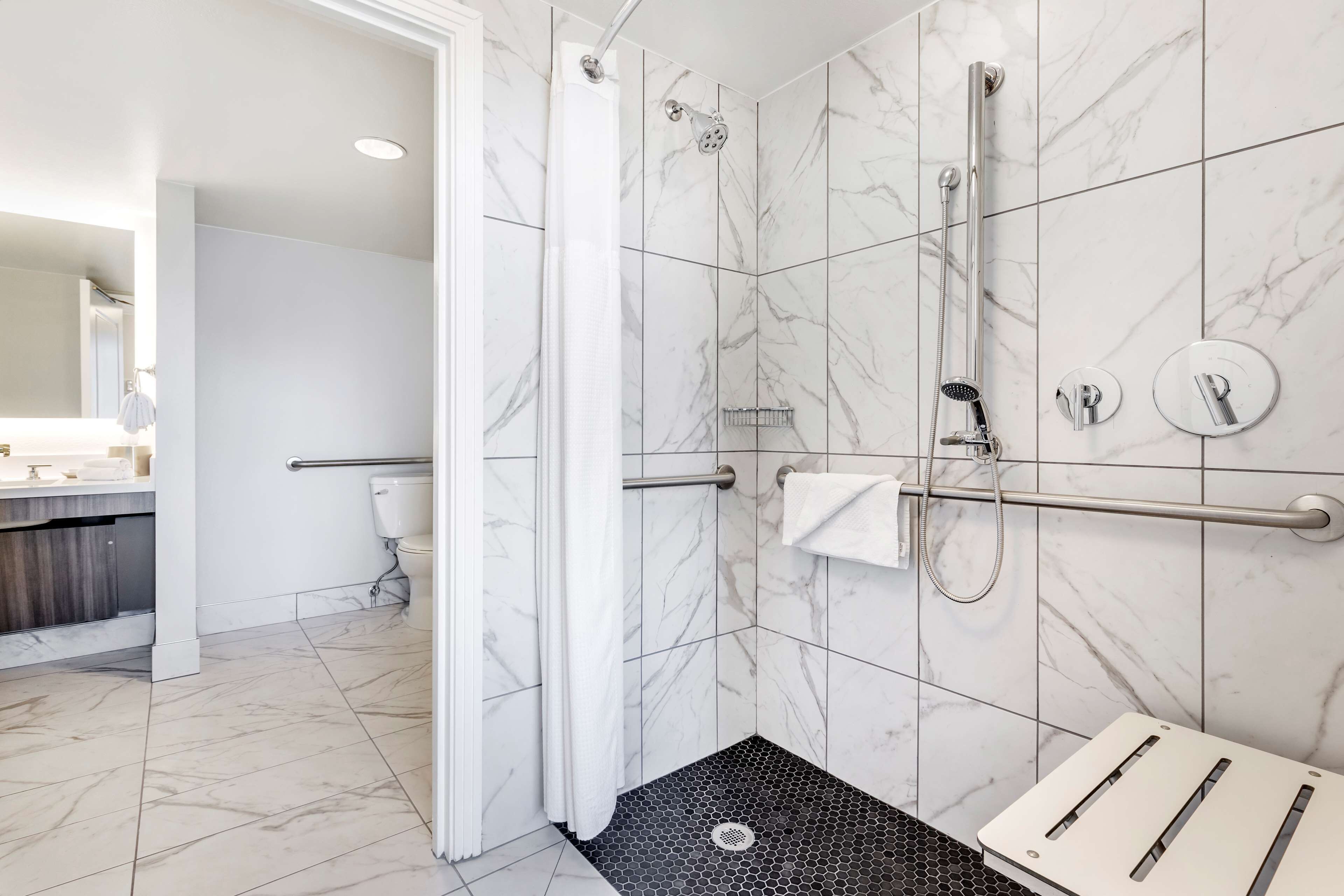 A modern bathroom with a shower, toilet, and sink.