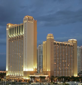 A hotel pool area with a waterfall feature, lounge chairs, and a bar area. at Hilton Grand Vacations Club on the Las Vegas Strip