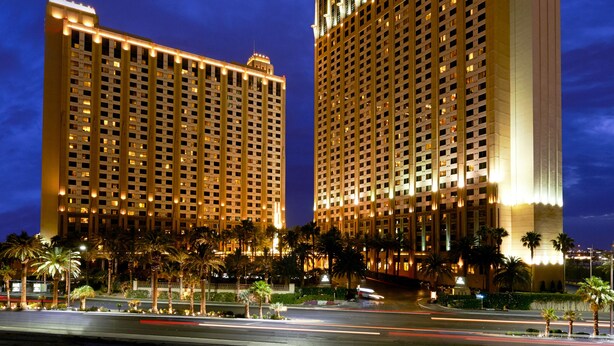 Two high-rise buildings with illuminated windows and a clear sky.