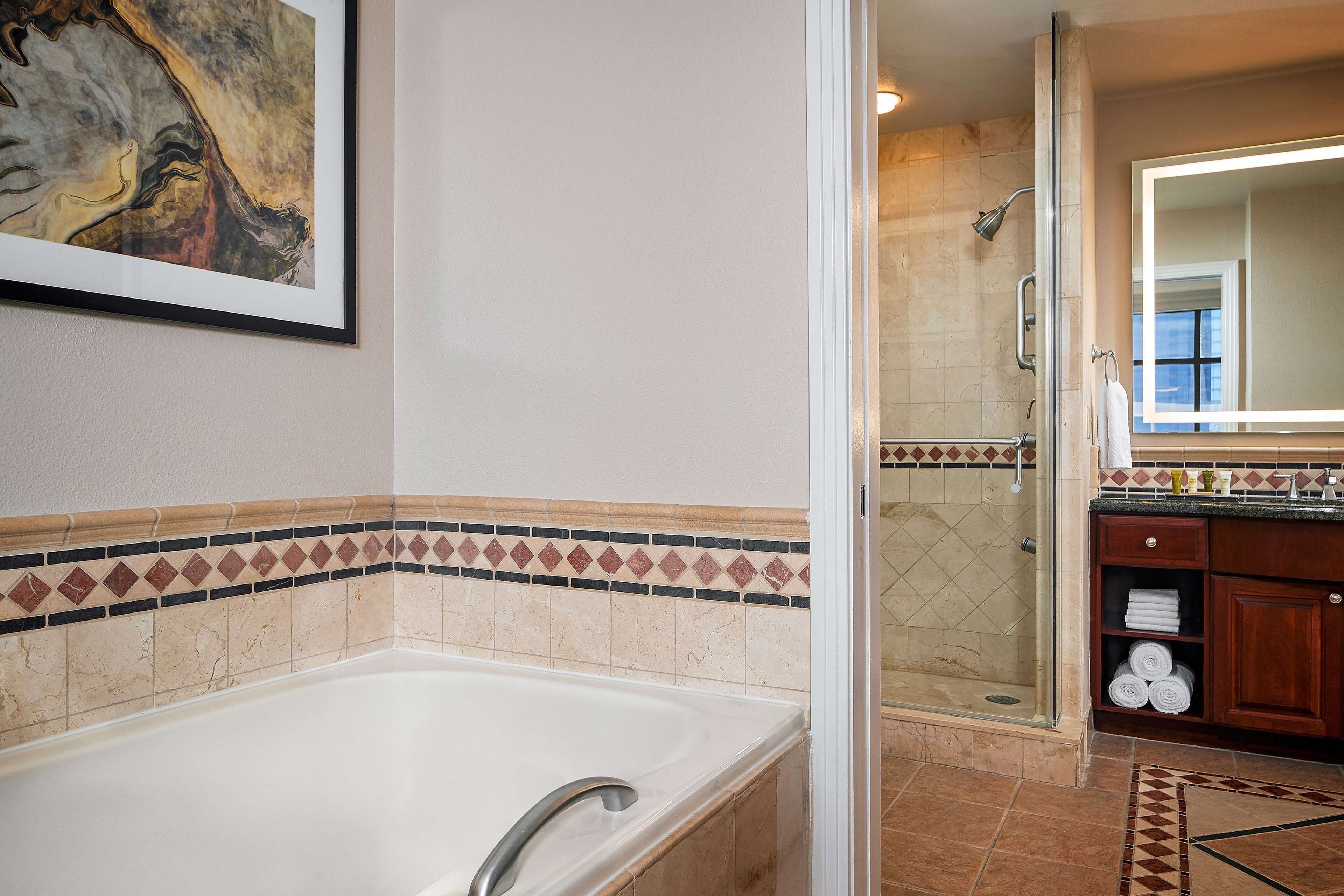 A modern bathroom with a bathtub, shower, and a large mirror.