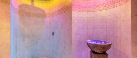 A spa room with a stone bathtub, a stone basin, and a curved ceiling with a light fixture.