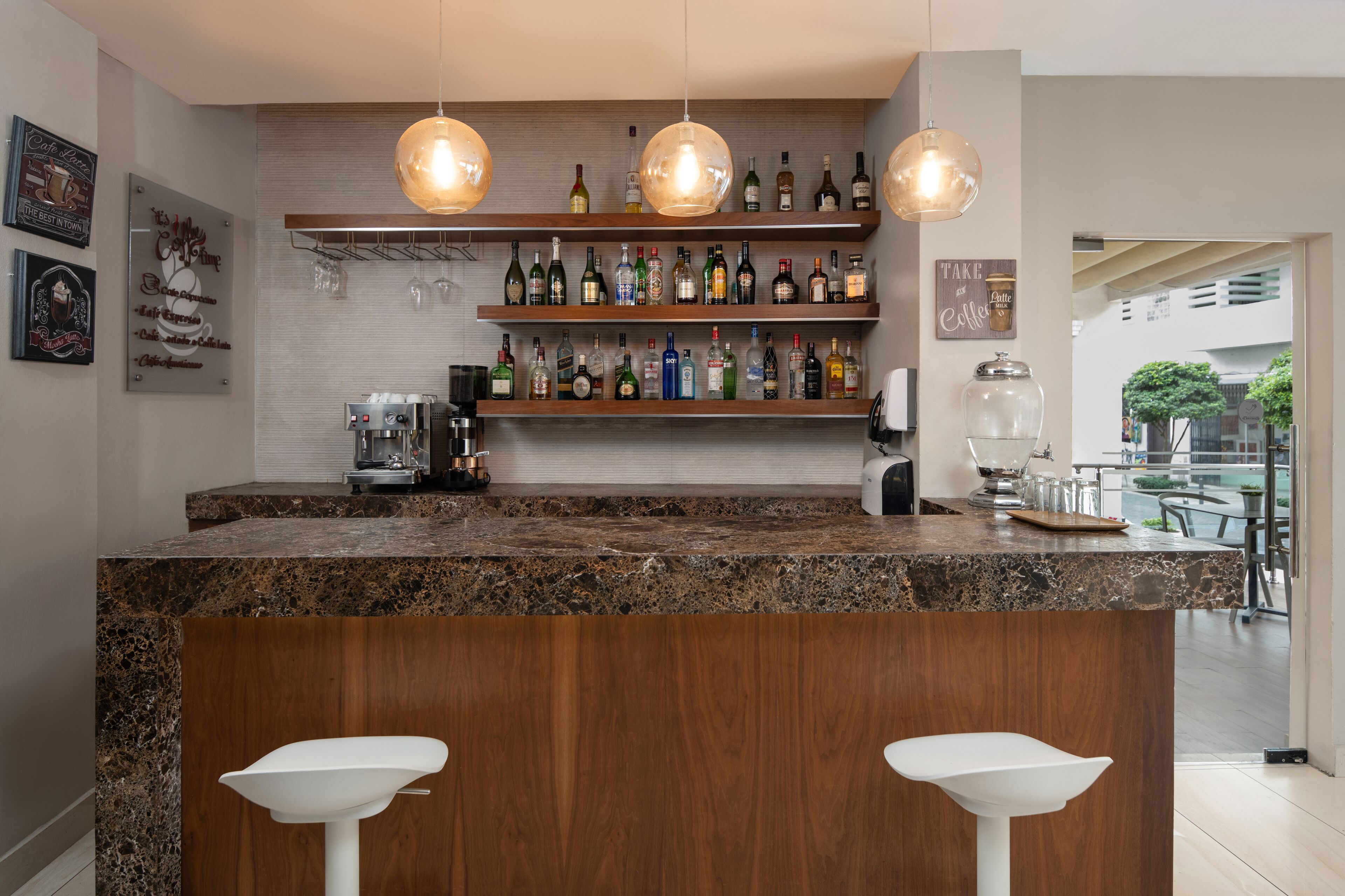 A modern kitchen with a marble island, wooden bar counter, and hanging pendant lights.