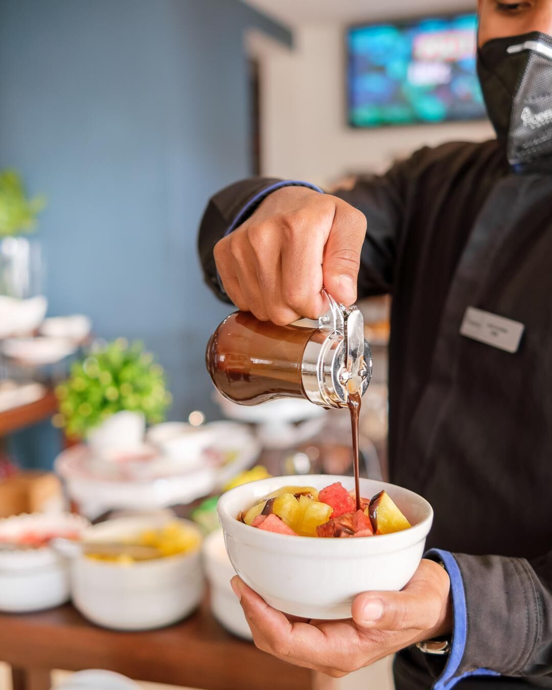 A person pouring a beverage into a bowl containing fruit.