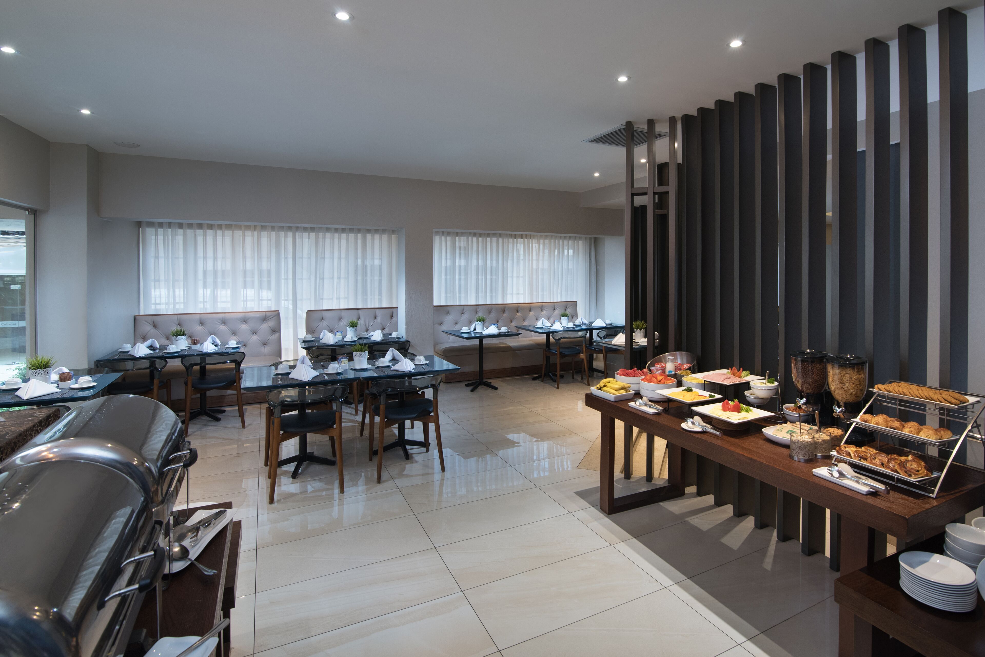 En moderne spiseplads med flere borde, et buffetbord med forskellige retter og en grillstation.