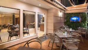 A modern restaurant with a glass entrance, wooden tables, and chairs.