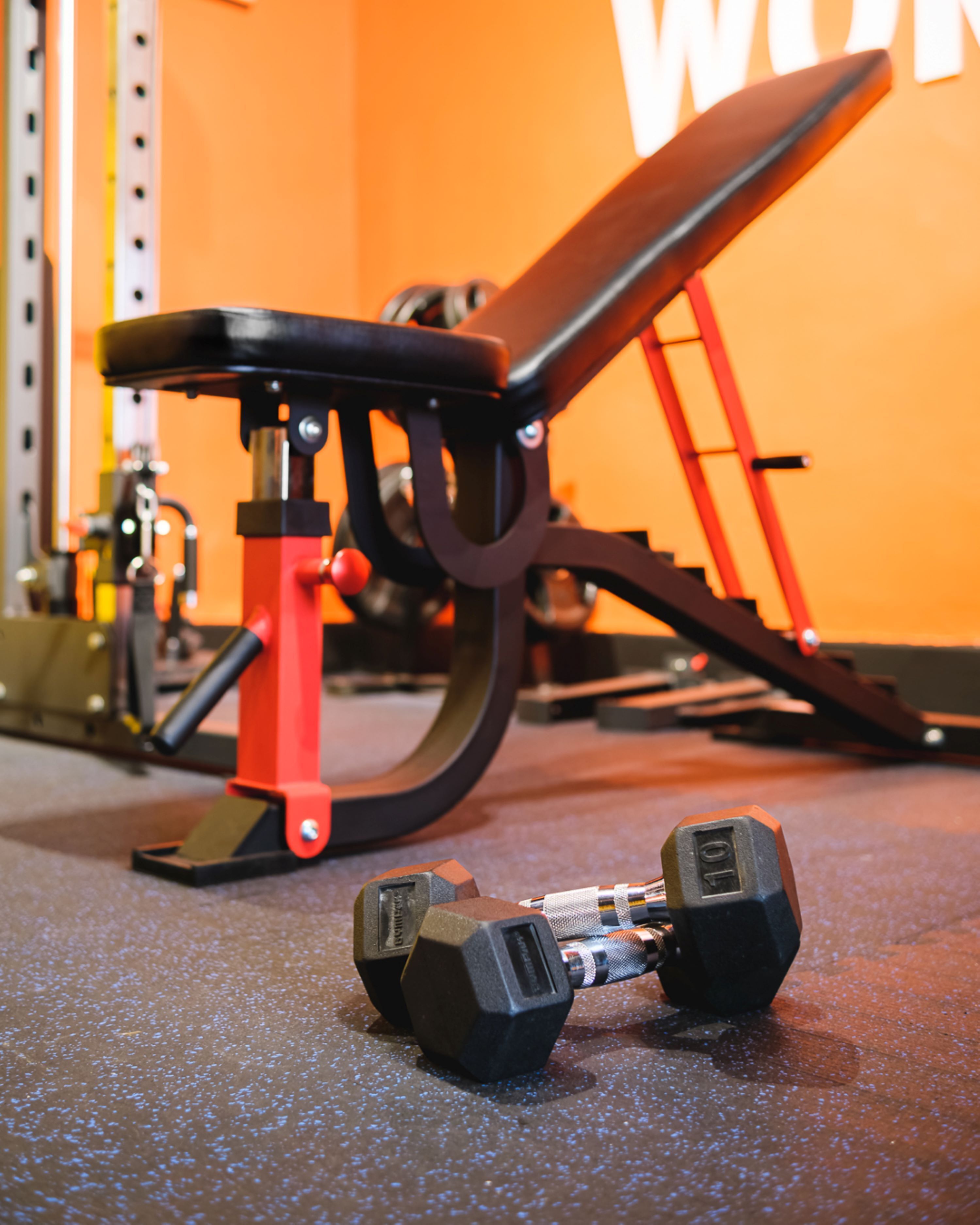 A gym with exercise equipment, including dumbbells and a bench.