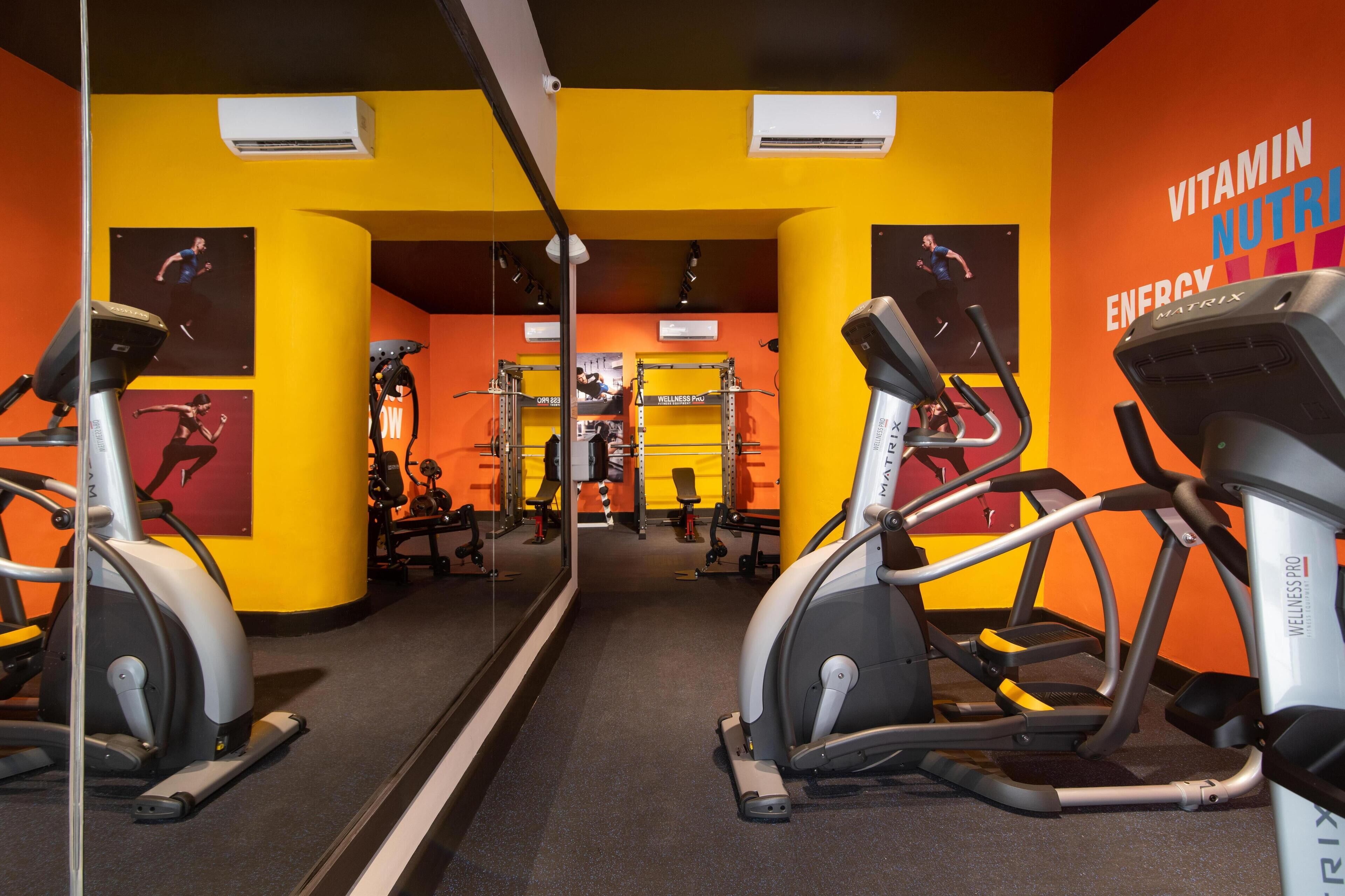 A gym with exercise equipment, mirrors, and motivational posters.
