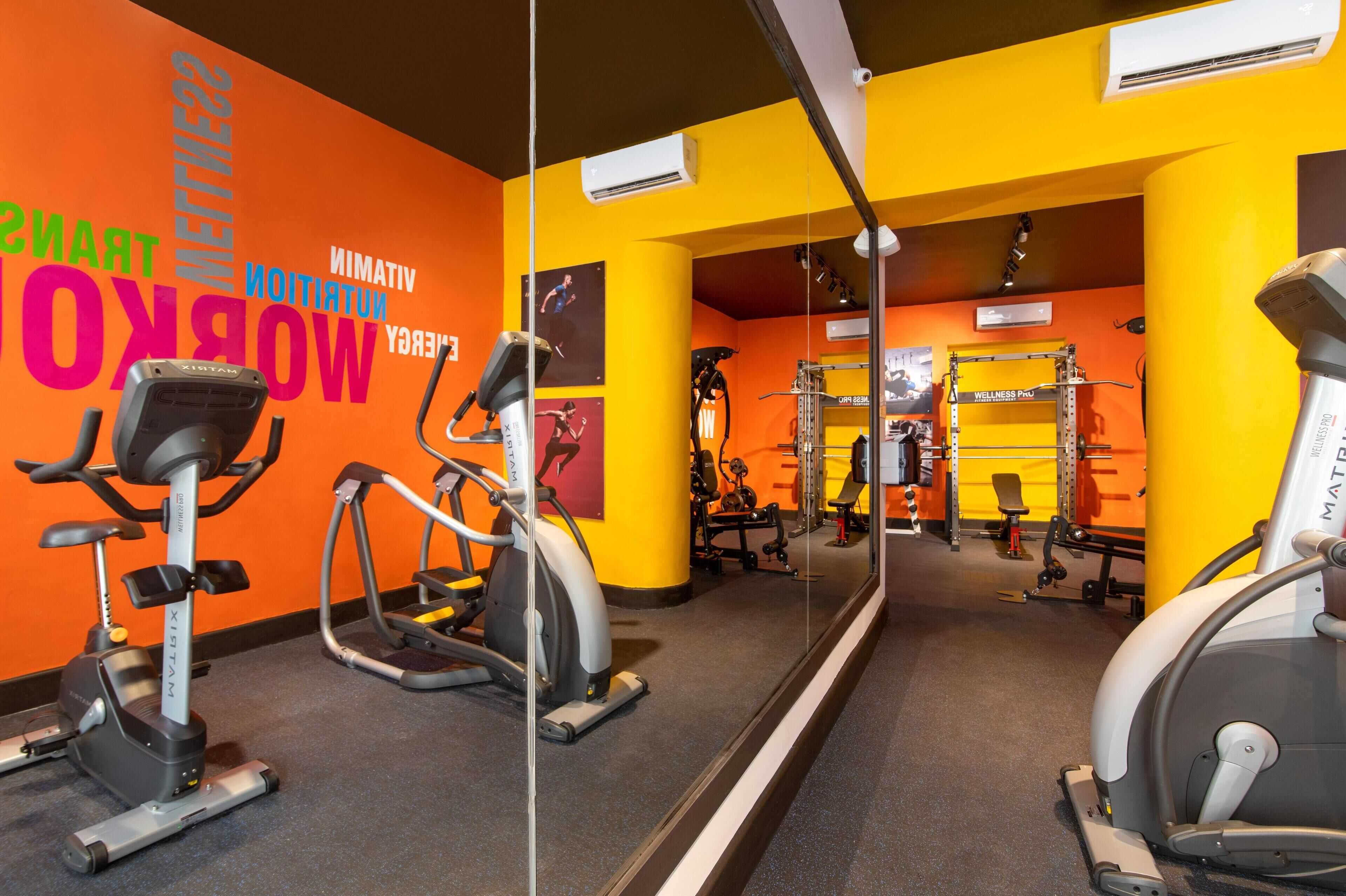A gym with various exercise equipment, including treadmills and stationary bikes, and motivational words on the wall.