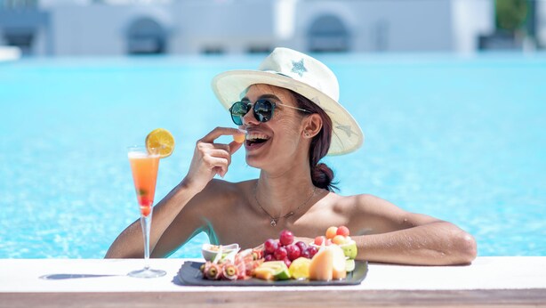 A person relaxing by a pool with a tray of fruit and a drink. - Hodelpa Gran Almirante Hotel & Casino (Santiago de los Caballeros)