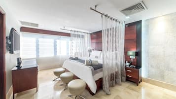 A modern hotel room with a bed, bedside table, TV, and a desk with a chair.