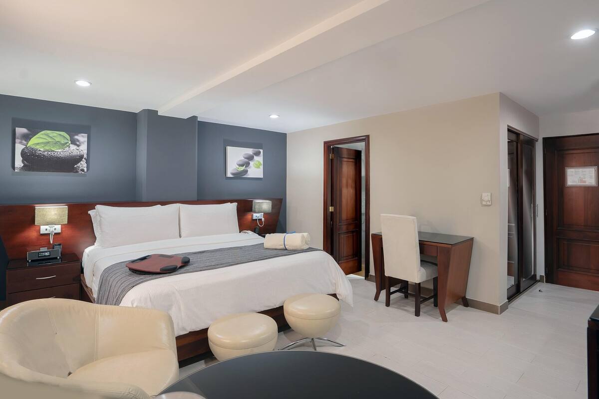 A hotel room with a bed, bedside tables, a desk, and a chair.