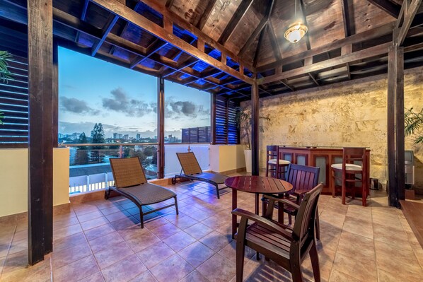 Relax in a charming outdoor seating area with a round table and comfortable chairs, offering a view of the city.