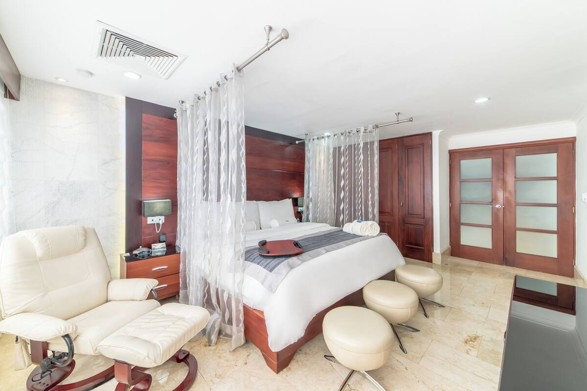 A bedroom with a bed, bedside table, chair, and a wardrobe.