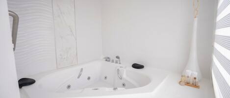 A modern bathroom with a large bathtub, a shower area, and a vanity with a mirror.
