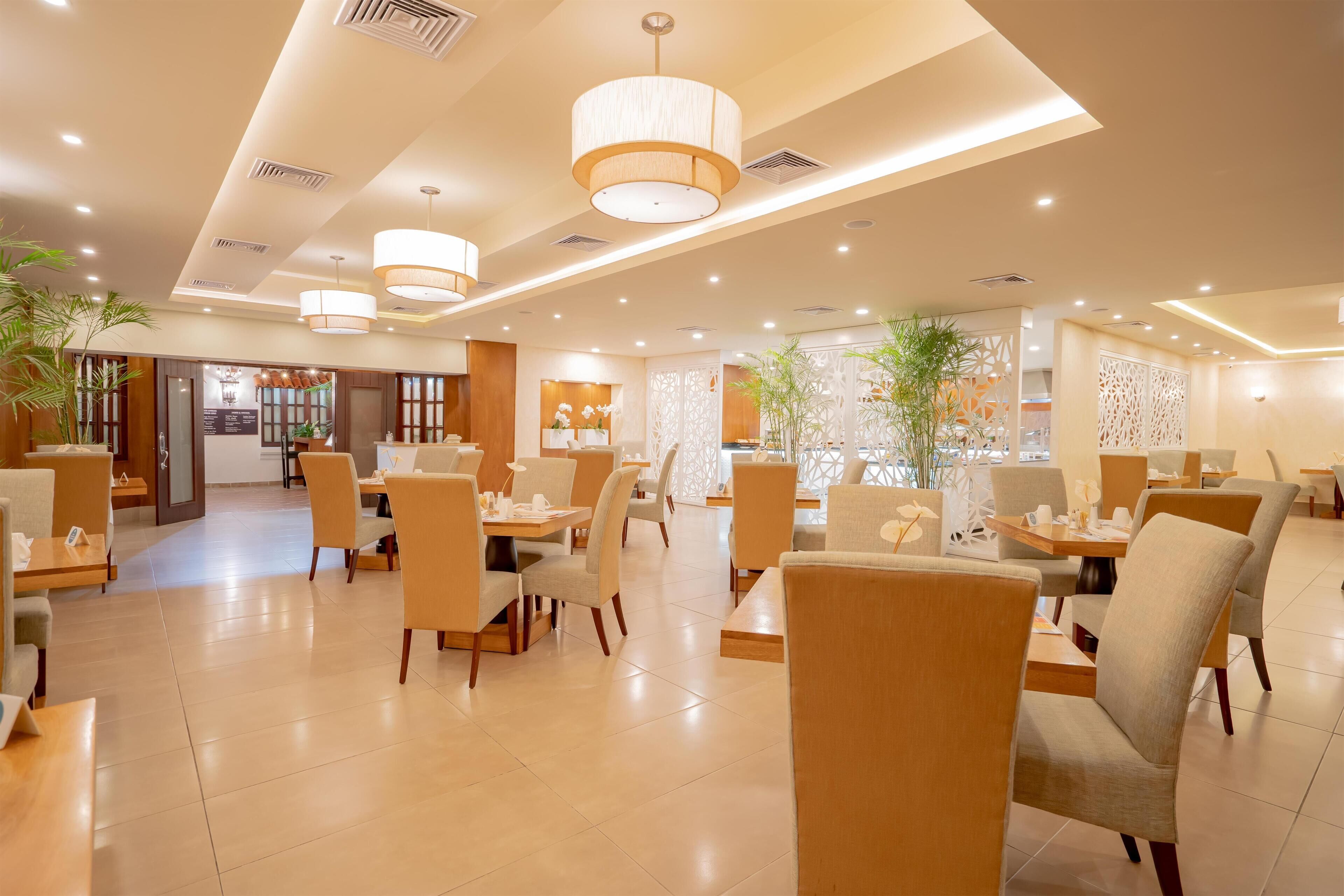A spacious hotel lobby with modern furniture, recessed lighting, and decorative plants.
